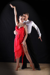 Latino dancers in ballroom against on black