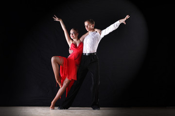 Latino dancers in ballroom against on black