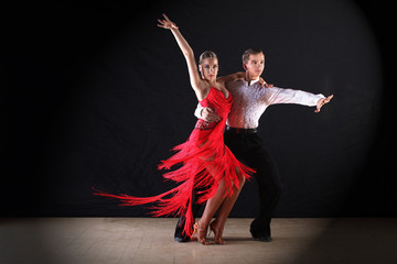 Latino dancers in ballroom against black background