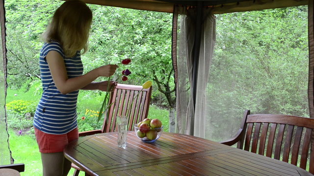 Blond woman soak dap tulip flowers and apple fruit in glass dish