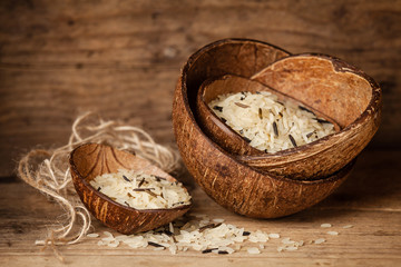 Fototapeta na wymiar Mixed basmati and wild rice in bowl of coconut on wooden backgro