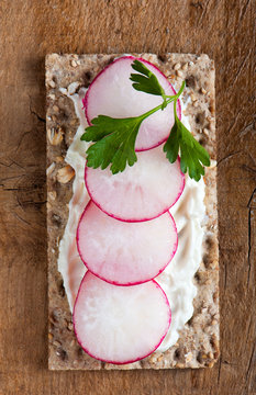 Radishes on crispbread on a wooden background