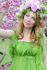 Fototapeta premium Beautiful girl in a flowered garden peach