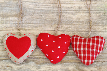 Fototapeta premium Three canvas hearts on wooden surface