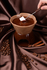 Chocolate fondue with marshmallow candies, on brown background
