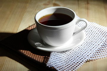 Cup of hot beverage on color wooden background, in dark
