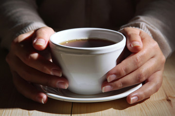 Hands holding mug of hot drink, close-up