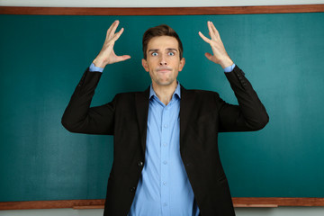 Young teacher near chalkboard in school classroom