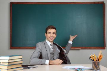 Young teacher sitting in school classroom