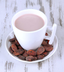 Cocoa drink and cocoa beans on wooden background