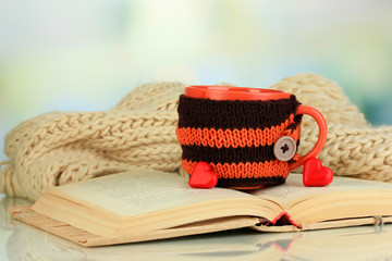 Fototapeta premium Cup with knitted thing on it and open book close up