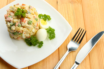 Russian traditional salad Olivier, on wooden background