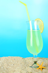 Beach cocktail in sand on blue background