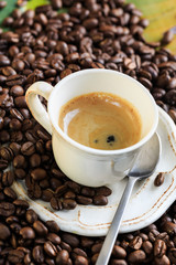 Cup of coffee with a creamy surface and coffee beans