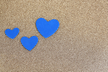 Blue hearts made of felt on golden background