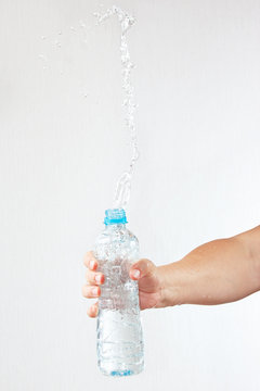 Female hand shaking a bottle of fresh water with a splash