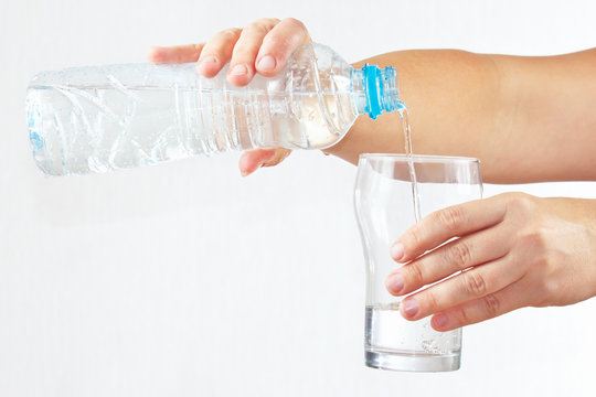 Female hand pour fresh water into a glass from bottle