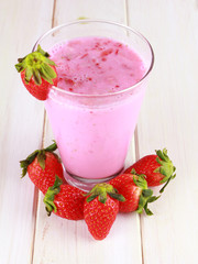 glass of strawberry smoothie on a wooden background