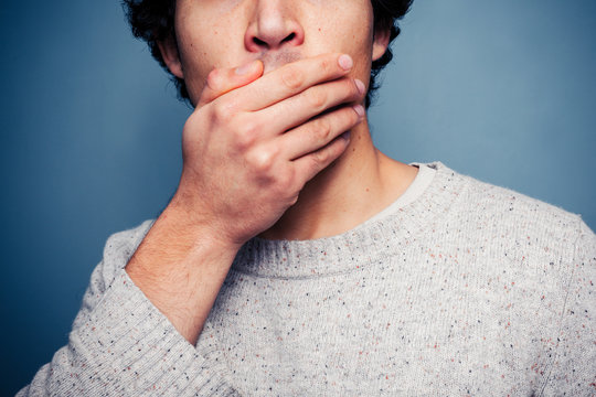 Shocked young man with his hand on his mouth