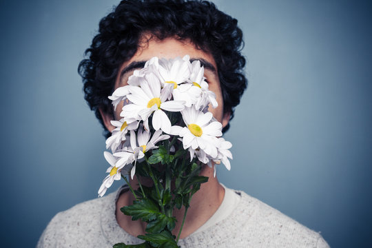 Young man hiding behind flowers