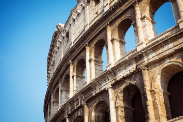 Fototapeta premium Detail of the Coliseum against the blue sky. Italy