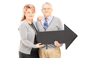Fototapeta premium Smiling mature man and woman holding a big arrow pointing right
