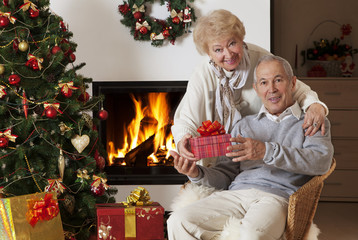 Obraz na płótnie Canvas Senior couple exchanging Christmas gifts