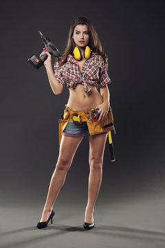 Hot female construction worker holding drill