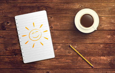 Notizblock mit Sonne Zeichnung Stift und Kaffee auf Holz Tisch