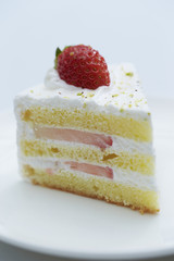 Piece of cake on white plate with strawberries