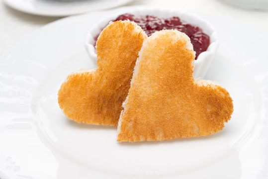 Two toast bread in the shape of hearts and berry jam, close-up