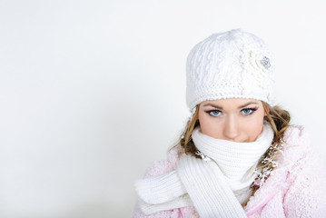 The young beautiful girl in a white cap and a scarf on a white b