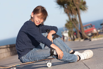 boy with cool attitude sitting on skateboard outdoors