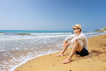 Fototapeta na wymiar Lost male tourist sitting on a beach and thinking