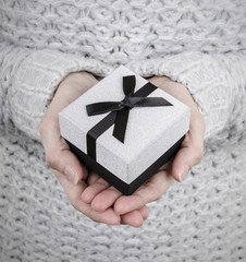 woman holding silver gift box with black ribbon