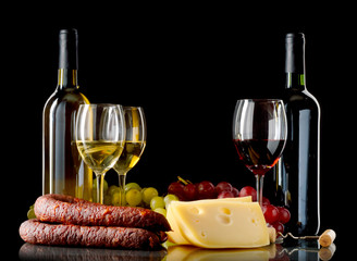 Wine, grapes, cheese and sausage on black background