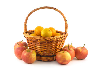 Many orange tangerines in brown wicker basket and apples