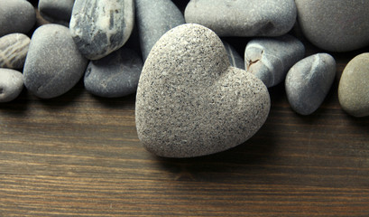 Fototapeta na wymiar Szary kamień w kształcie serca, na tle drewniane