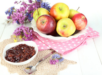 Juicy apples on plate on white wooden table
