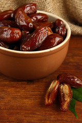 Dried dates in bowl on table on sackcloth background