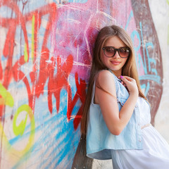 hipster girl outdoors stands near a graffiti wall
