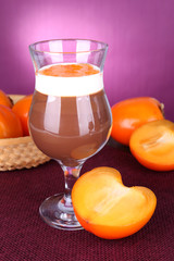 Dessert of chocolate and persimmon on table on purple