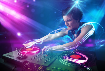 Energetic Dj mixing music with powerful light effects