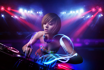 Disc jockey girl playing music with light beam effects on stage
