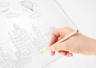 A person drawing sketch of a city with balloons and clouds on a