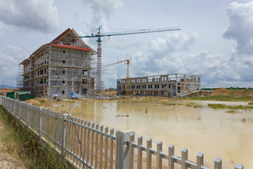  It shows construction cranes and unfinished house on the skylin