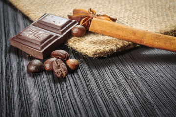 Chocolate bar and spices on wooden table