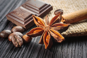 Chocolate bar and spices on wooden table