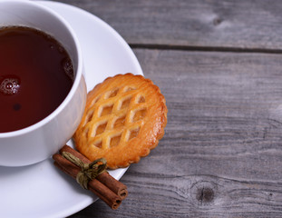 Cookies with cinnamon and cup of tea on wooden background