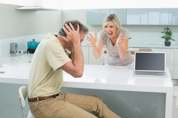 Man covering his ears as woman argue in kitchen